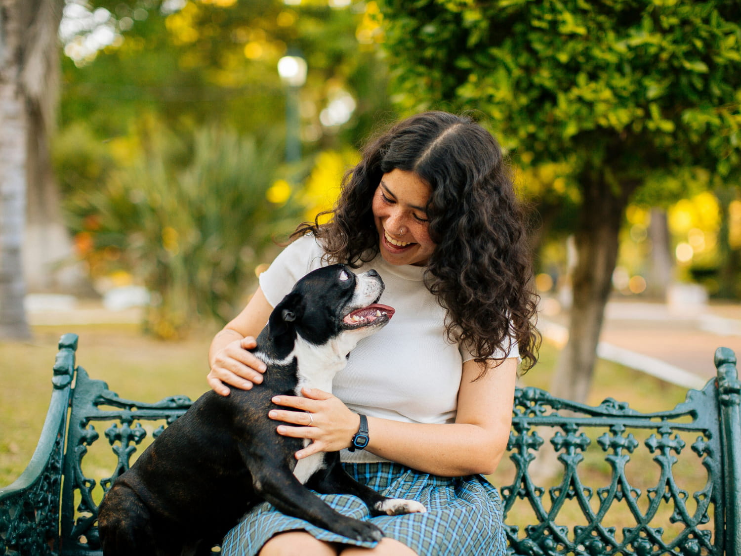 Happy girl sitting with happy dog on a bench